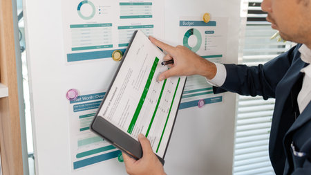 A professional businessman presenting financial analysis on charts, discussing marketing strategies and company goals to drive profitability, growth, and sustainable business development.の写真素材