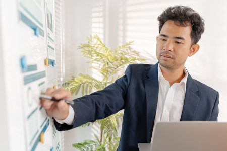 A business analyst examining charts and statistics on a whiteboard, using data-driven insights to guide financial strategy, business performance, and future organizational planning.の写真素材