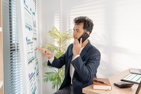 A business analyst examining charts and statistics on a whiteboard, using data-driven insights to guide financial strategy, business performance, and future organizational planning.の写真素材