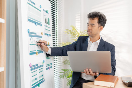 A business analyst examining charts and statistics on a whiteboard, using data-driven insights to guide financial strategy, business performance, and future organizational planning.の写真素材