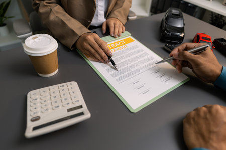 A business meeting between a car dealer and a client discussing vehicle purchase agreement. The contract is being reviewed and explained before signing, representing trust and cooperation.の写真素材