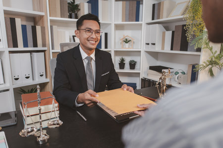 A professional lawyer discussing legal matters with a client in an office, providing legal advice and document review services, symbolizing justice, trust, and professional consultation.の写真素材