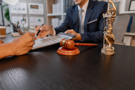 A professional lawyer discussing legal matters with a client in an office, providing legal advice and document review services, symbolizing justice, trust, and professional consultation.の写真素材