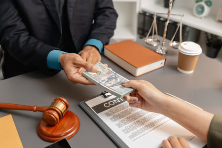 A client is handing money to a lawyer sitting at a desk, symbolizing a payment for legal services, contract agreement, or settlement process in a professional business environment.の写真素材