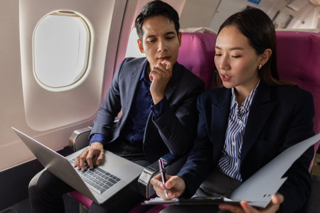 A moment during a flight where a manager appears to be discussing work with his assistant. The woman looks upset while holding documents in a tense discussion.の写真素材