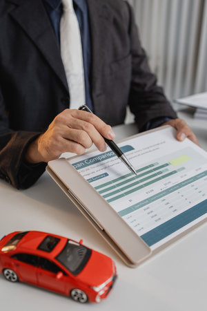 A businessman in a suit is calculating loan details, reviewing financial documents, and holding car...