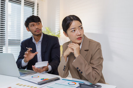 A group of business professionals engaged in a serious office discussion, analyzing financial reports and exchanging ideas to solve problems and make effective corporate decisions.の写真素材