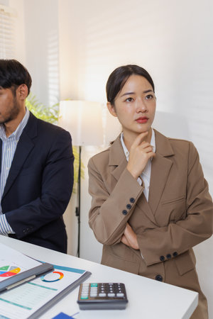 A group of business professionals engaged in a serious office discussion, analyzing financial reports and exchanging ideas to solve problems and make effective corporate decisions.の写真素材
