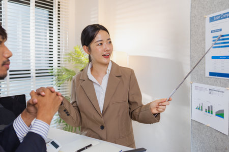 Business colleagues are actively engaged in a collaborative meeting, reviewing charts, pointing at data, and exchanging ideas. Their teamwork reflects strategy planning, analysis, and cooperation.の写真素材