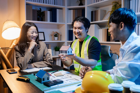 Architects and engineers work together in an office to review blueprints, exchange ideas, and refine their building plans for a contemporary construction project in an urban setting.の写真素材