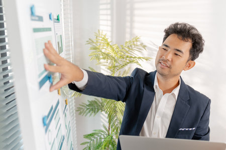 A business analyst examining charts and statistics on a whiteboard, using data-driven insights to guide financial strategy, business performance, and future organizational planning.の写真素材