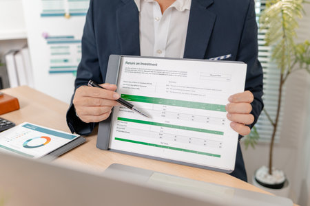 A confident businessman calculating budget and reviewing company performance using reports and charts in a clean modern office, focusing on financial goals, investments, and strategic success.の写真素材