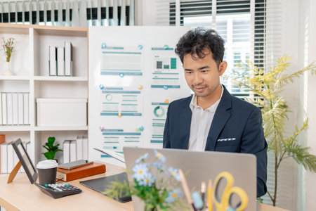 A businessman in a suit analyzing financial charts and performance reports in a bright modern office, focusing on strategy, data, and budget planning for company growth and long-term success.の写真素材