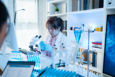A chemistry researcher in a laboratory surrounded by scientific equipment and test tubes, representing innovation, scientific development, and modern medical research environment.の写真素材