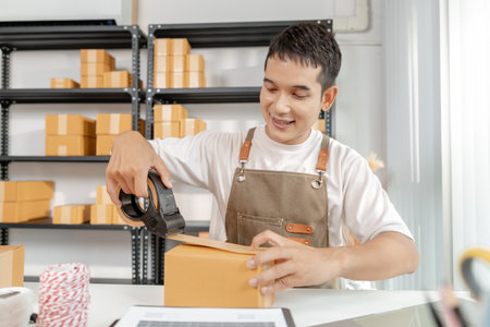 Startup business in ecommerce sector, with young professional managing online trade, packaging goods, and highlighting the importance of digital platforms in retail success.の写真素材