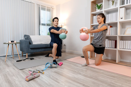 A young couple exercising together at home, smiling and enjoying their workout routine. They focus on staying fit and maintaining a healthy lifestyle through home fitness and mutual motivation.の写真素材