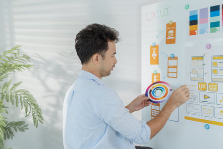 A creative designer is working on UX UI planning, reviewing wireframes, and adjusting color schemes...
