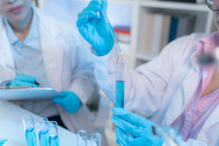 Two chemists in white lab coats working together in a modern laboratory surrounded by scientific...