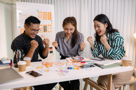 UX/UI designers collaborating during a creative workshop to test interface ideas and exchange feedback for app development, emphasizing teamwork and innovative design thinking.の写真素材