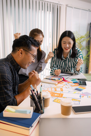UX/UI designers collaborating during a creative workshop to test interface ideas and exchange feedback for app development, emphasizing teamwork and innovative design thinking.の写真素材