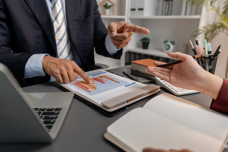 Business professionals reviewing financial charts and performance reports during a meeting, highlighting strategic planning, budget analysis, and teamwork in a modern corporate environment.の写真素材