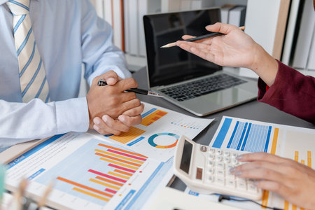 Business colleagues reviewing budget charts together in a modern office, focusing on financial insights, performance metrics, and strategic planning to support upcoming business decisions.の写真素材