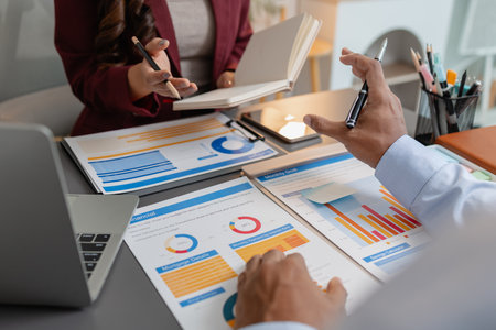 Business colleagues reviewing budget charts together in a modern office, focusing on financial insights, performance metrics, and strategic planning to support upcoming business decisions.の写真素材