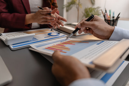 Business professionals reviewing financial charts and performance reports during a meeting, highlighting strategic planning, budget analysis, and teamwork in a modern corporate environment.の写真素材