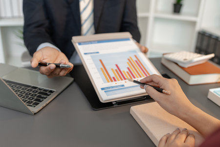 Business professionals reviewing financial charts and performance reports during a meeting,...