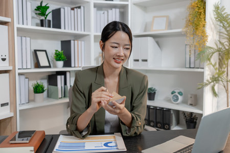 Professional businesswoman reviewing financial reports and taking notes at her workspace, focused on planning, decision making, and data analysis to support strategy and effective management.の写真素材