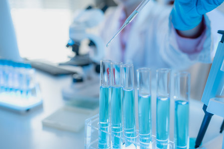Two female scientists in white lab coats working together in a bright laboratory with microscopes,...