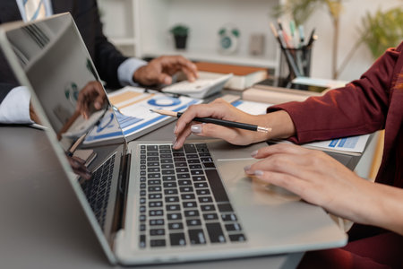 A business meeting scene where professionals review financial charts and exchange insights,...
