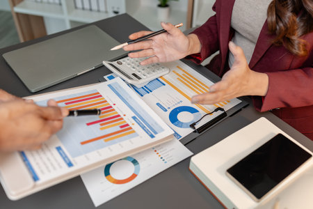 Business professionals meeting at a modern office table, reviewing charts and budget reports while...