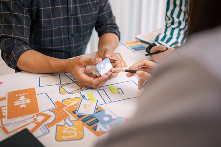 A group of UX/UI designers brainstorming creative ideas together, discussing color palettes and...