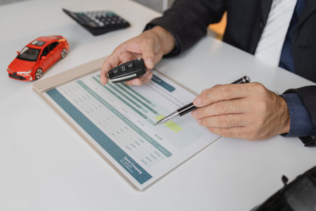 A businessman in a suit is calculating car loan options using a calculator and comparison chart,...