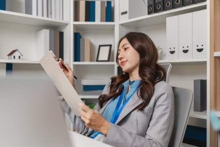 Smiling businesswoman working on a laptop in a modern office, reviewing reports and analyzing data...