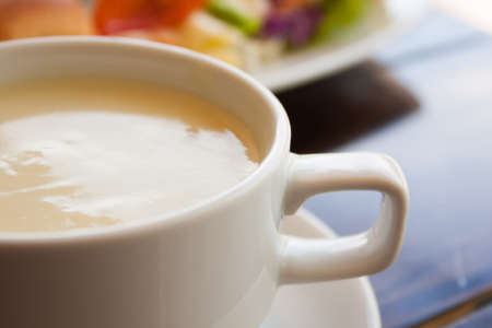 cream soup in white cup on wooden tableの写真素材