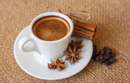 cup of coffee with cinnamon and beans on sackの写真素材