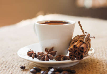 cup of coffee with cinnamon and beans on sackの写真素材