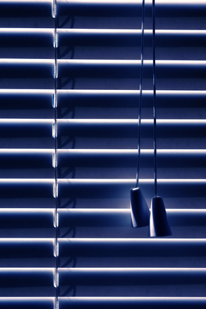 Closed blinds, located on the window, protect from the sun during the bright day or from the neon light of the city at night. With space for text.の写真素材