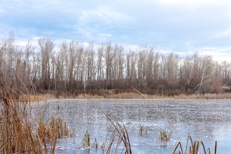 Winter landscape ice-covered lake and trees. Beautiful cloudy sky. Incredible nature in natural...