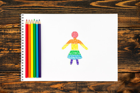 Paper women doll cut from paper and painted in LGBT colors. Concept of LGBT. On the left side of the colored pencils painted in the colors of the flag LGBT. Top view.の写真素材
