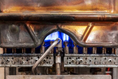 Old worn copper gas boiler without protective casing. The boiler is in operation mode. close up...