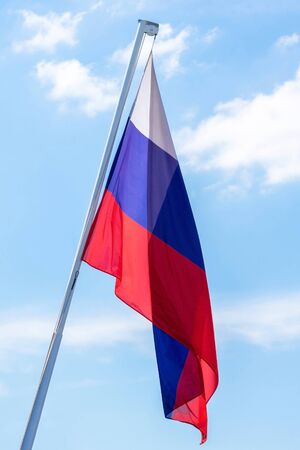 The flag of the Russian Federation in a quiet state against the blue sky. Vertical photo.の写真素材