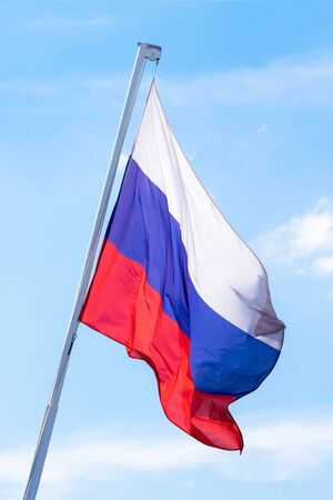 The flag of the Russian Federation is developing against the blue sky. Vertical photo.の写真素材