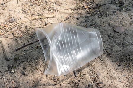 Plastic trash on the forest. Environmental pollution problem. Trash on sand. crumpled disposable plastic Cup. Concept of world environmental problem. forest pollution with plastic debris. Problem of ecology.の写真素材