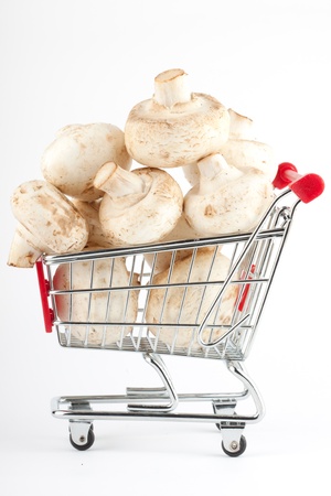 Buying healthy food. Shopping trolley with mushrooms on whiteの写真素材