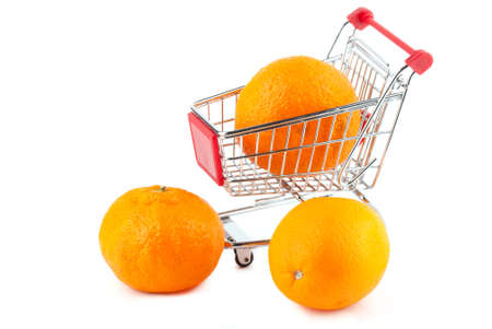 Buying healthy food. Shopping trolley with orange on whiteの写真素材