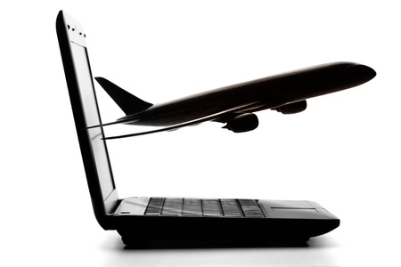 Laptop computer with airliner flying out from screen on a white backgroundの写真素材