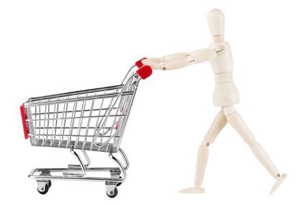 Shopping concept. Wooden dummy and metal shopping cart on a white backgroundの写真素材